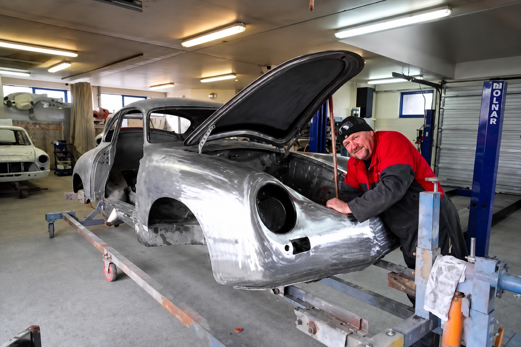 Bare metal classic car body on a rotisserie during a full restoration