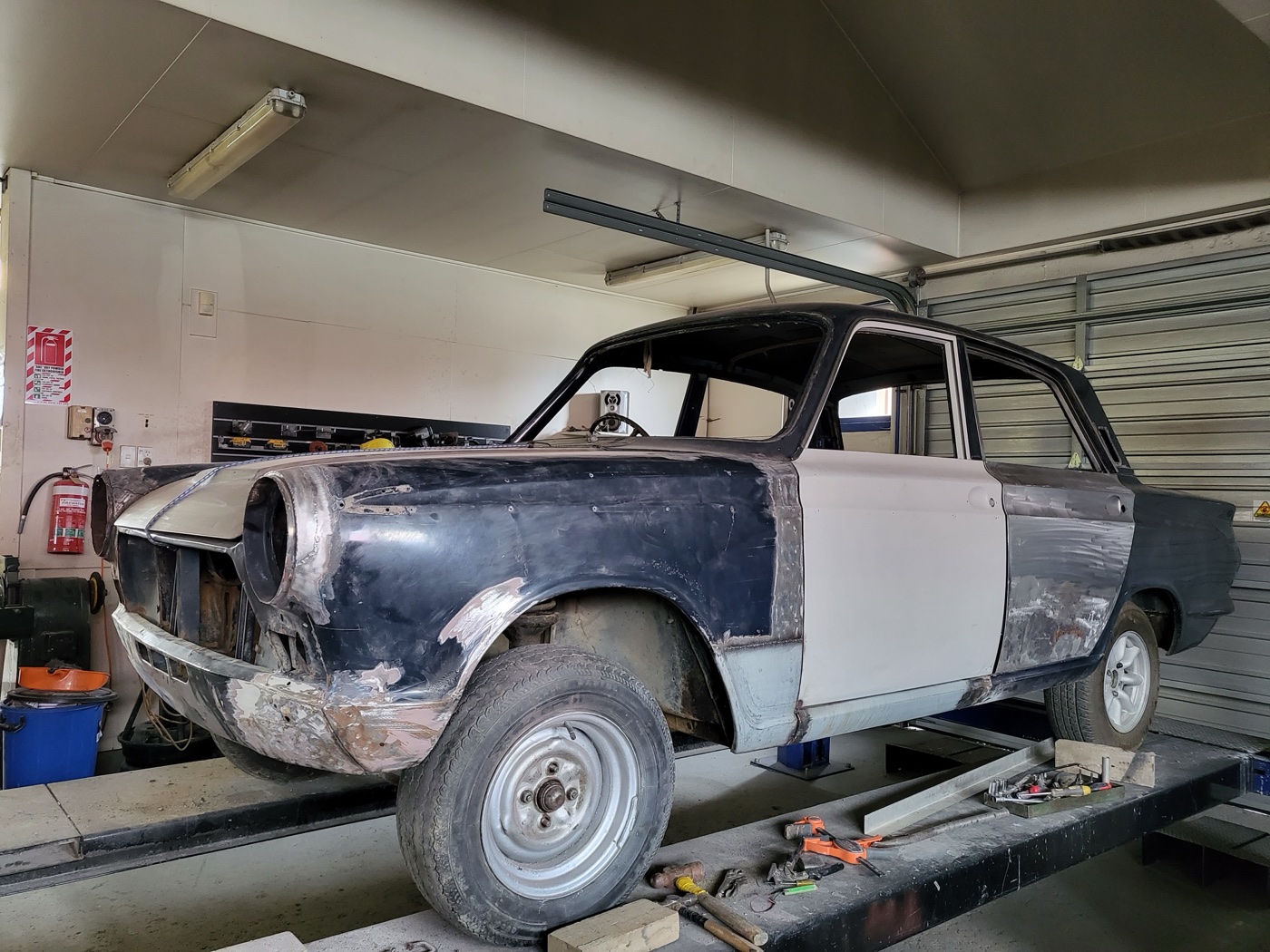 The Cortina part-stripped with panels in filler on the hoist